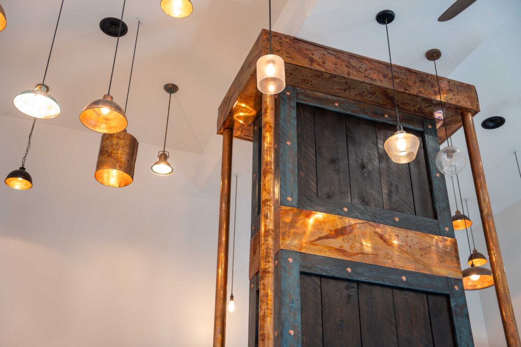 a very large custom made copper and wood hood above a luxurious commercial kitchen